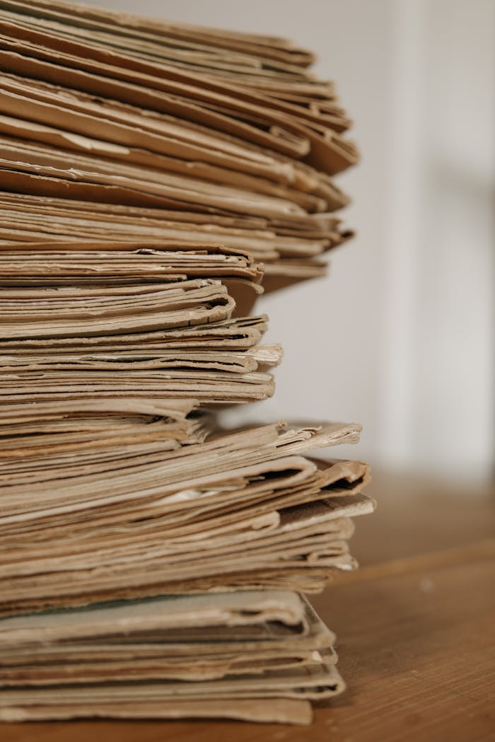 about-us Close-up of vintage paper stacks on a wooden table, evoking a classic office setting.